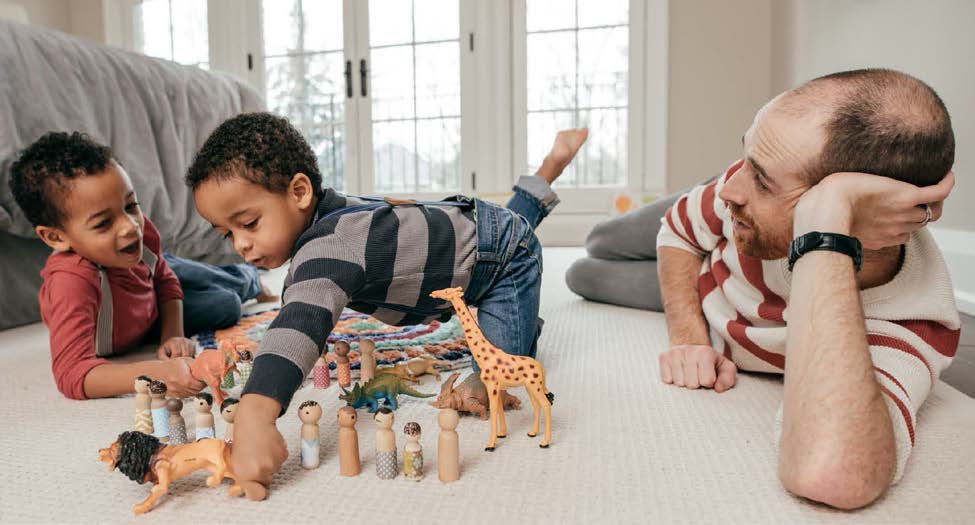 Father and 2 young boys playing with toys on the floor