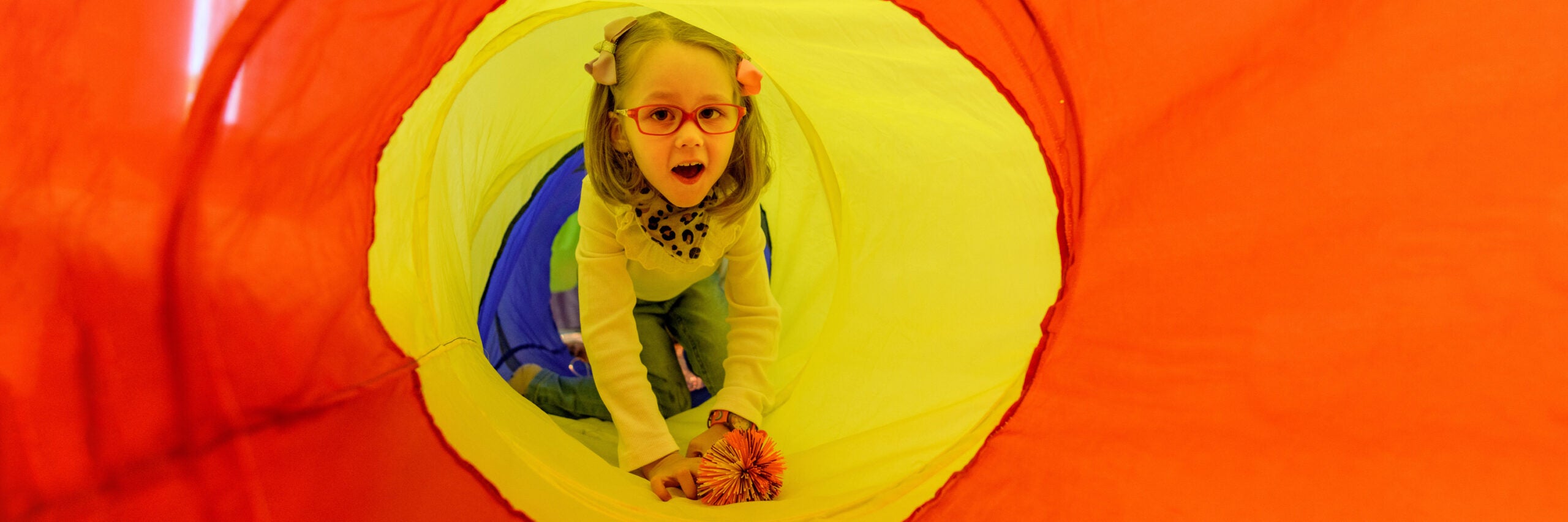 A girl living with cerebral palsy playing in a sensory room, snoezelen, during a therapy session